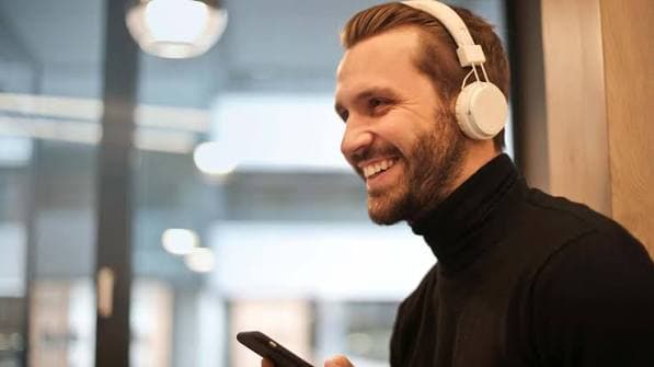 Person using headphones to convert article to audio while reading on their phone